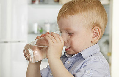 Little boy drinking a glass of water